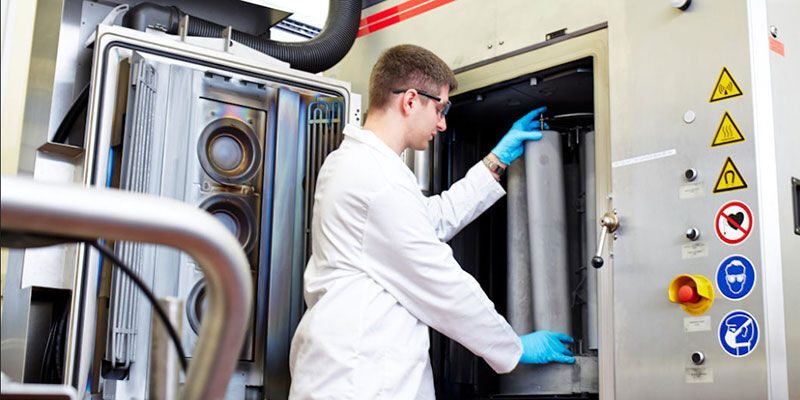 A functional surfaces researcher wearing safety gear assembles equipment.