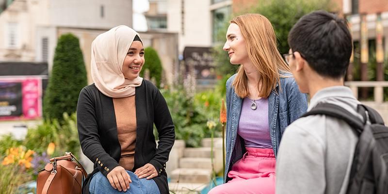 Three students talking in Millenium Square