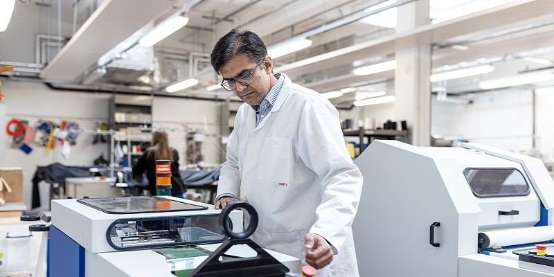 A lab technician in a white coat using the Yarn Spinning Line machine.