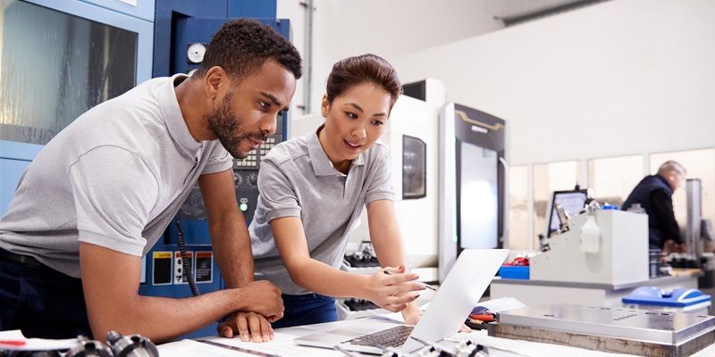 Two people in an engineering lab discussing something on a laptop.