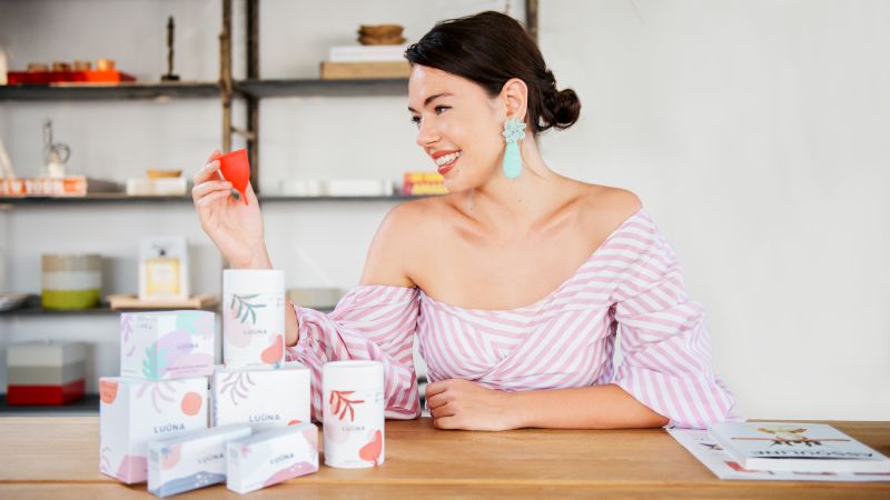 Olivia Cotes-James sat at a table with boxes of LUÜNA Naturals products on the table.