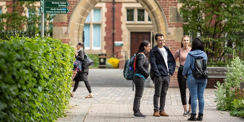 Three prospective students stood in front of Clothworkers Court on a campus tour led by a student ambassador