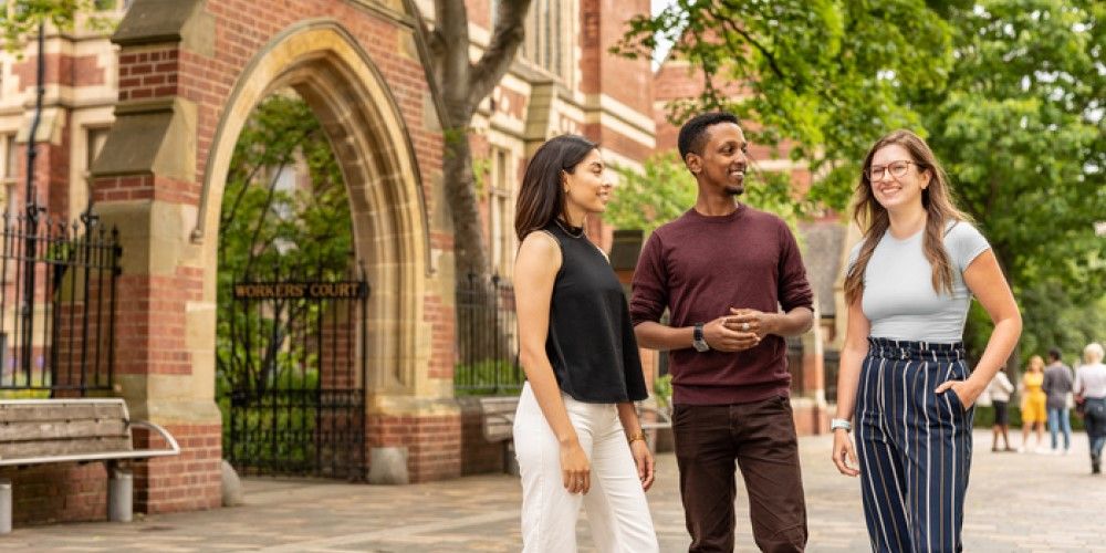 Three smiling students talking together outside the Clothworkers' Building.