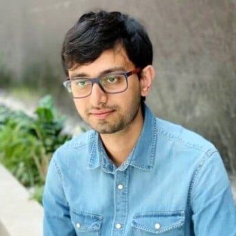 A headshot of Soumik. He looks to the left of the camera and wears a blue shirt and glasses.