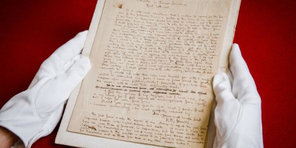 Handwritten letters signed by Branwell Brontë held by hands in white gloves