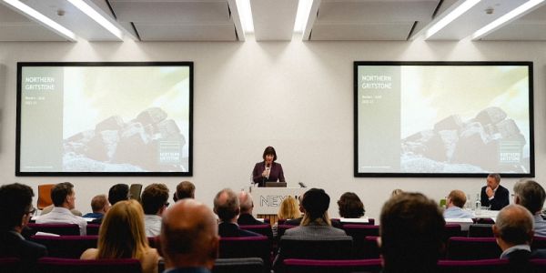 Rachel Reeves MP stands at a podium on a stage to address guests at Northern Gritstone's AGM.