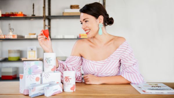 Olivia Cotes-James sat at a table with boxes of LUÜNA Naturals products on the table.