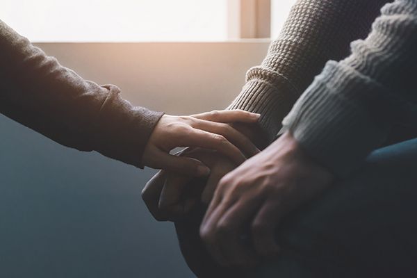 A hand reaches out to another in an act of comfort