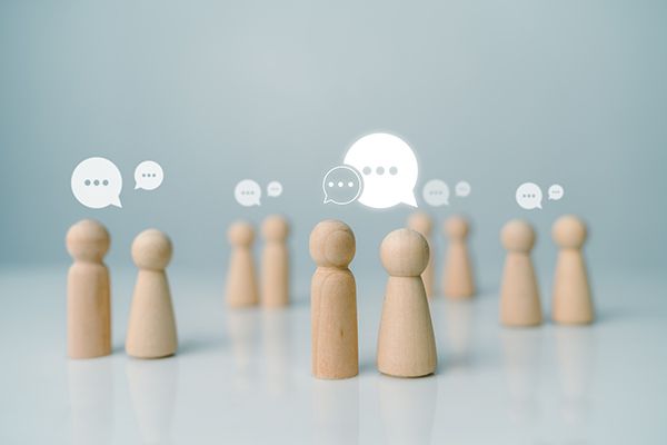 Wooden figures with speech-bubble graphics, representing many conversations happening at once