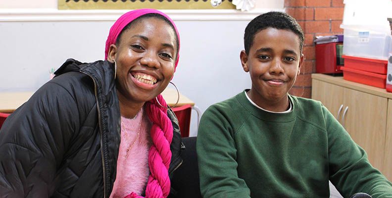 Eunica smiling with a school-age student.