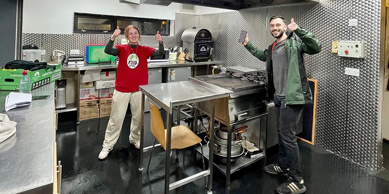 Two students working in a kitchen as volunteers.
