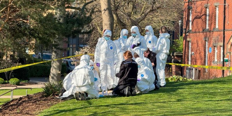 A police officer gathers schoolchildren around her who are covered up to prevent any forensic material being contaminated at the scene at the University of Leeds.