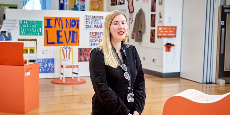 A picture of Jade French standing in front of an art exhibition.