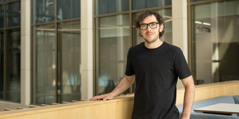Richard Mandle standing, wearing a black t-shirt, hand on shelf