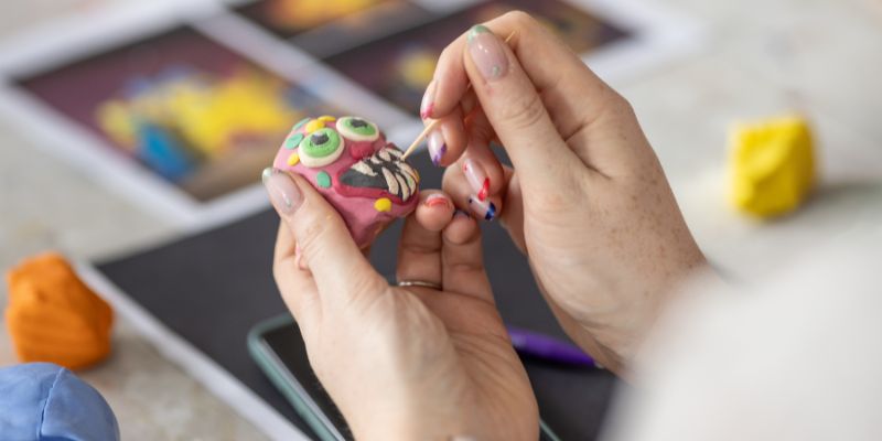 Hands creating a clay face sculpture