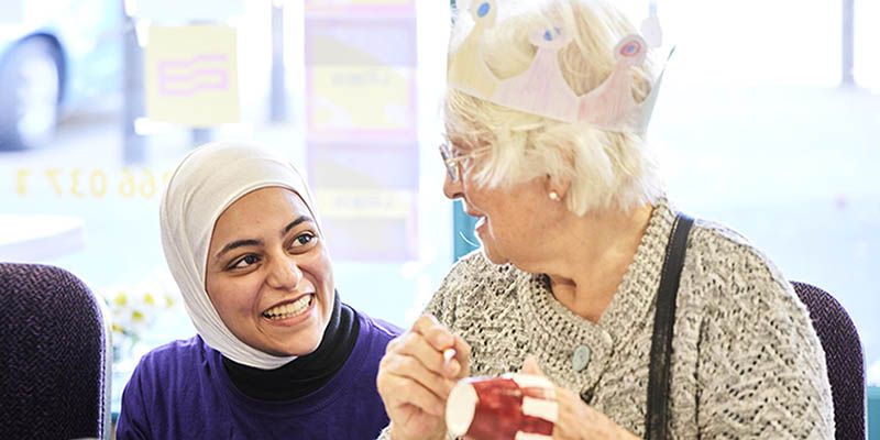 A student volunteer working with a member of the public at a table. Both are smiling.