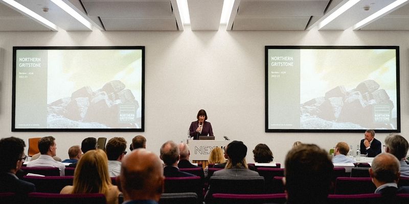 Rachel Reeves MP stands at a podium on a stage to address guests at Northern Gritstone's AGM.